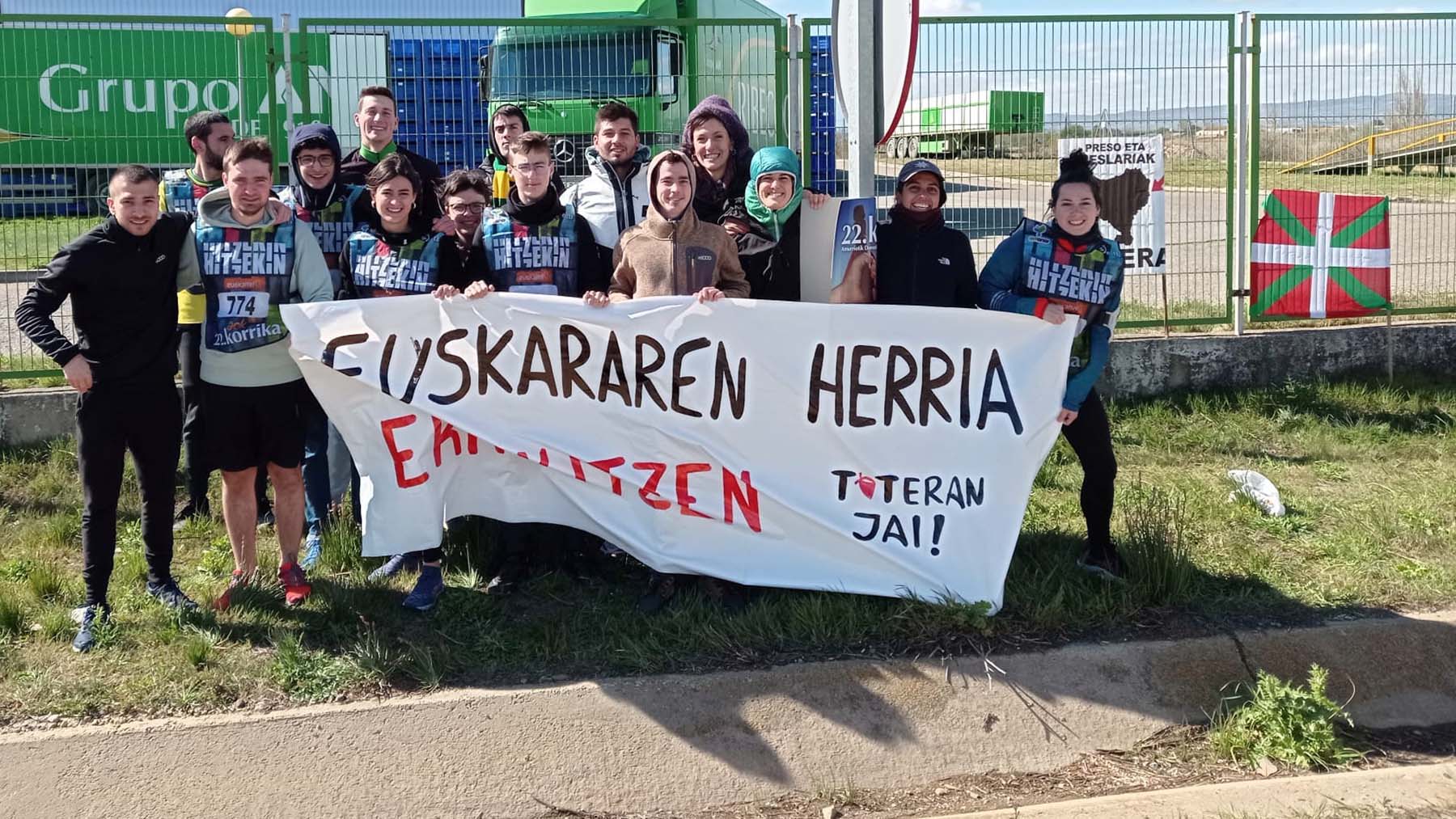 Miembros de Tuteran Jai posan durante un acto en favor del euskera junto a la ikurriña y una pancarta en favor de los asesinos de ETA.