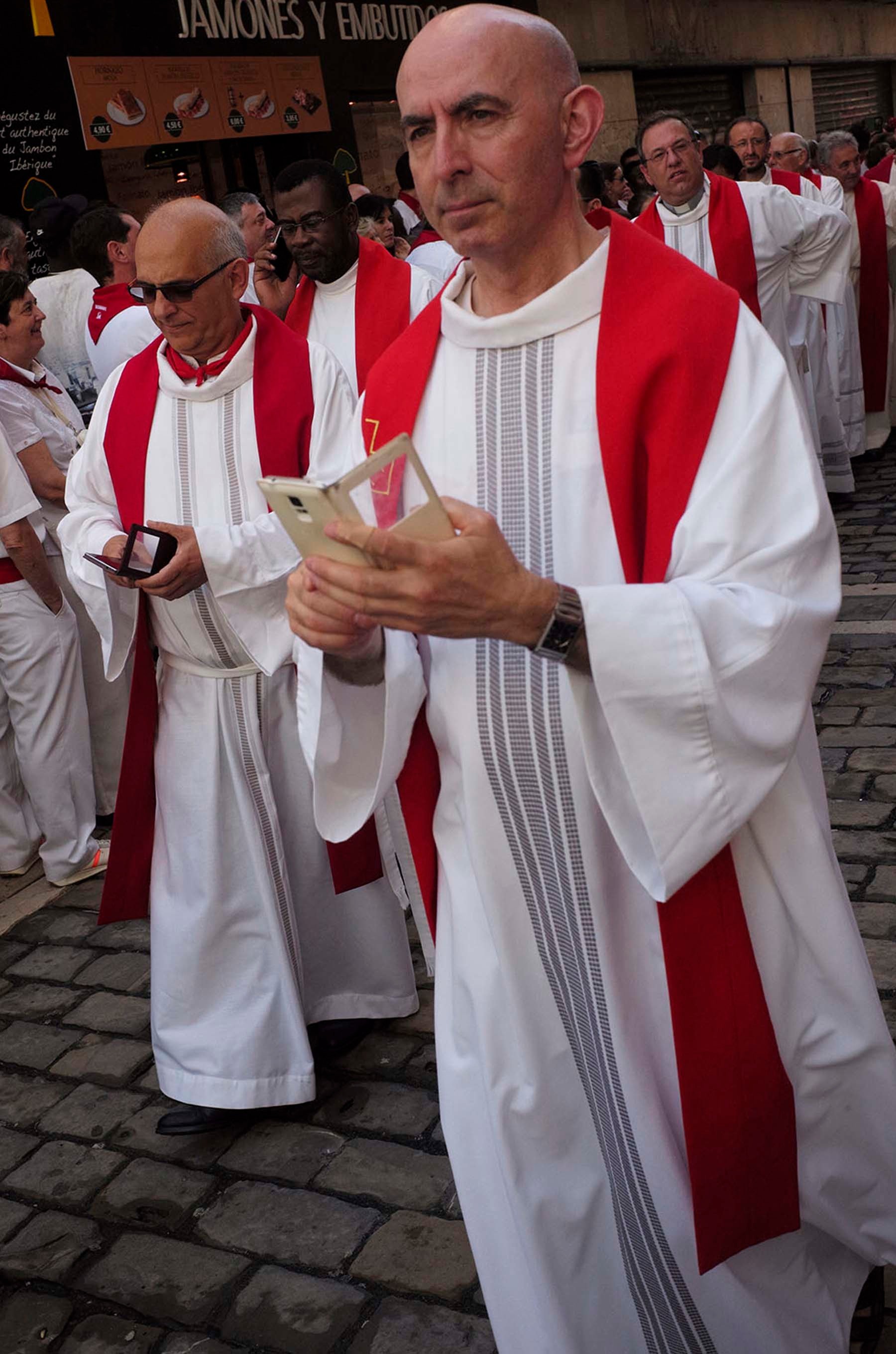 Los clérigos consultan con notable fervor el móvil durante la procesión. (Foto John Kimmich Javier, cortesía del autor)