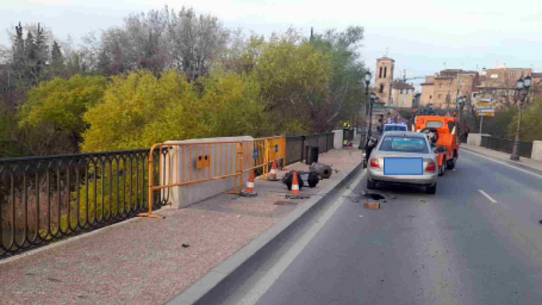 El coche siniestrado es retirado por la grúa. En la imagen se ve el trozo de valla arrancado de cuajo, así como las dos farolas que se llevó por delante. POLICÍA LOCAL DE TUDELA