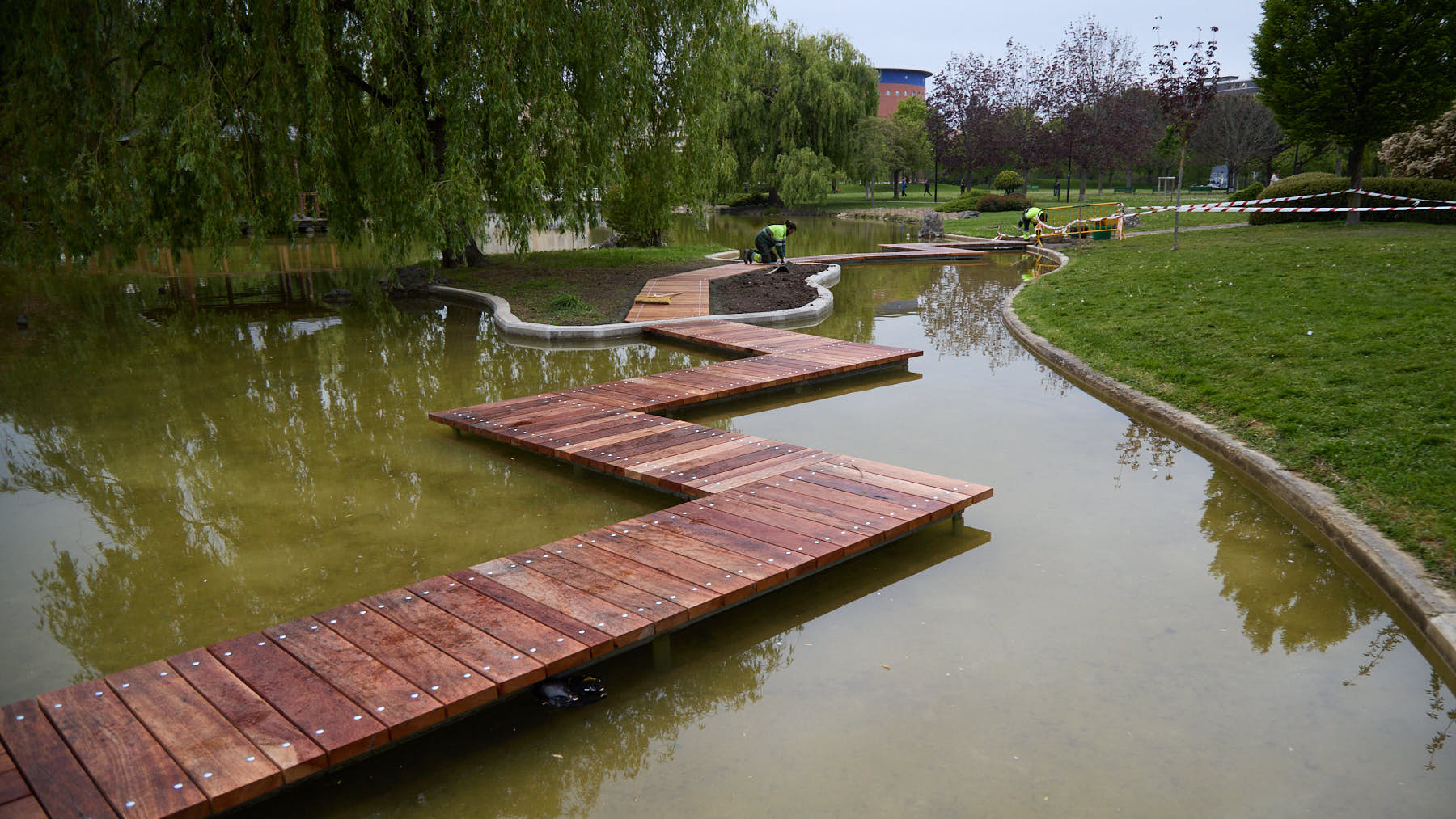 La nueva pasarela que conduce a la isla del bonito lago de un parque de Pamplona