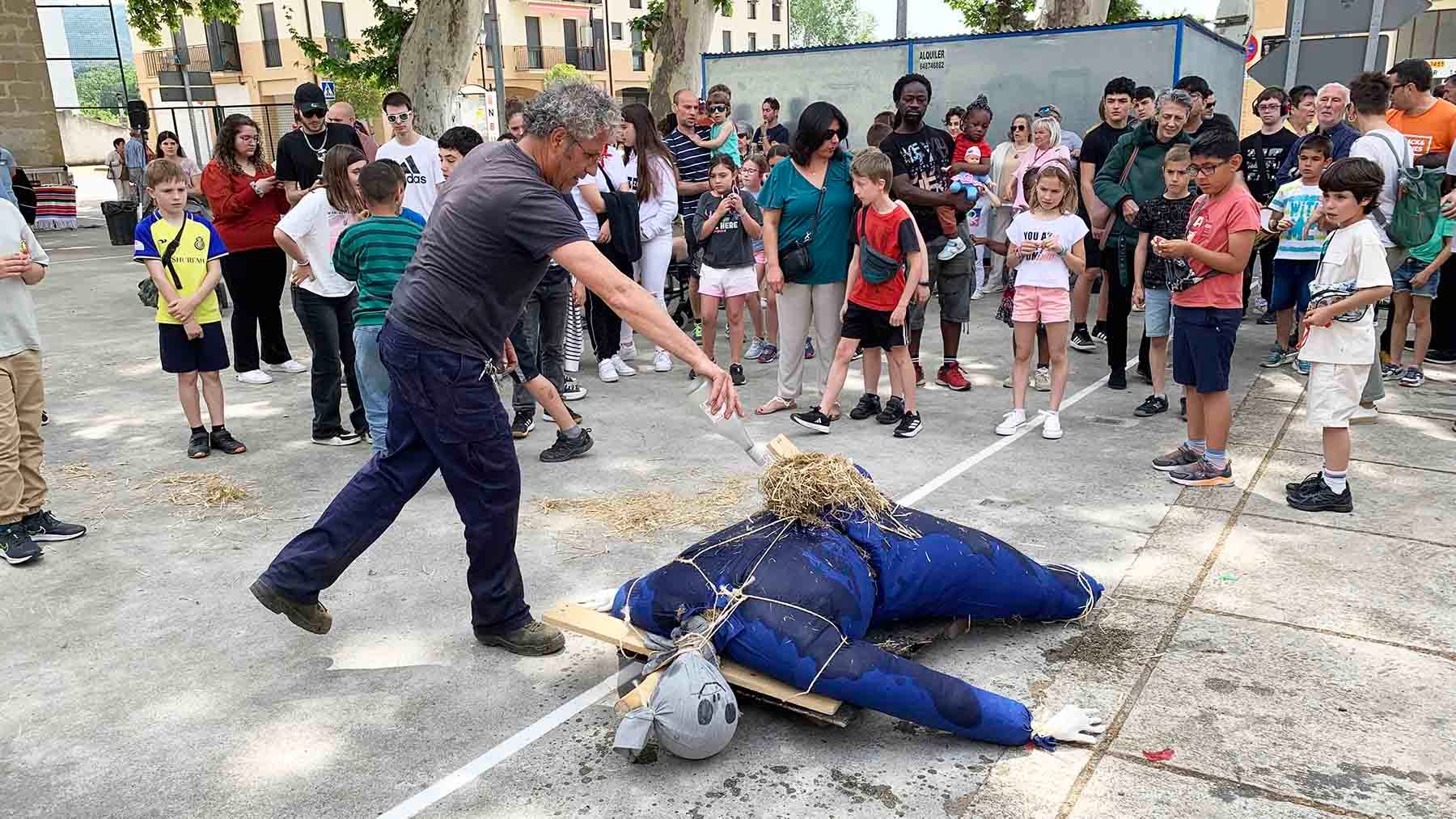 El empleado municipal rocía el 'mayo' con gasolina para prenderle una mecha y quemarlo en el frontón. Navarra.com