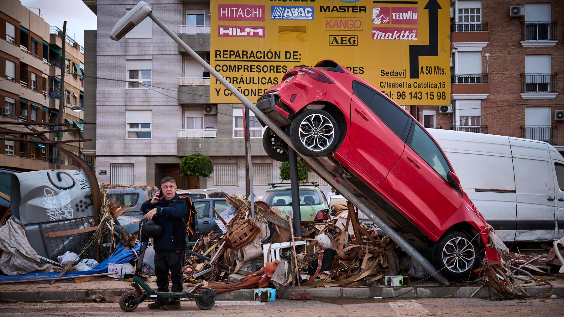 Un hombre habla por teléfono debajo de una farola con un coche, en Sedaví. PABLO LASAOSA