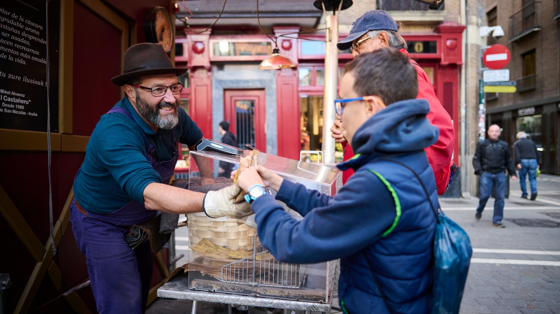 El castañero de San Nicolás, Mikel Álvarez Menor, entrega unas castañas asadas a un niño. PABLO LASAOSA