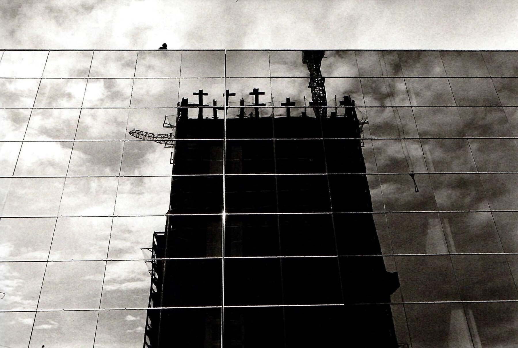 Foto 10. Torre Picasso en construcción en la que emergen una serie de cruces, reflejado el conjunto en otro edificio. Del reportaje monográfico El Santo Christo Ibérico. Madrid 1987. (Foto Koldo Chamorro, cortesía de la familia)