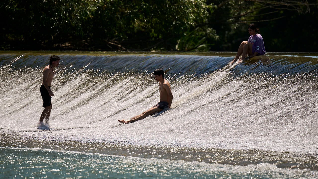 Decenas de personas aprovechan las altas temperaturas para refrescarse y disfrutar del r&iacute;o Arga a su paso por Pamplona. PABLO LASAOSA